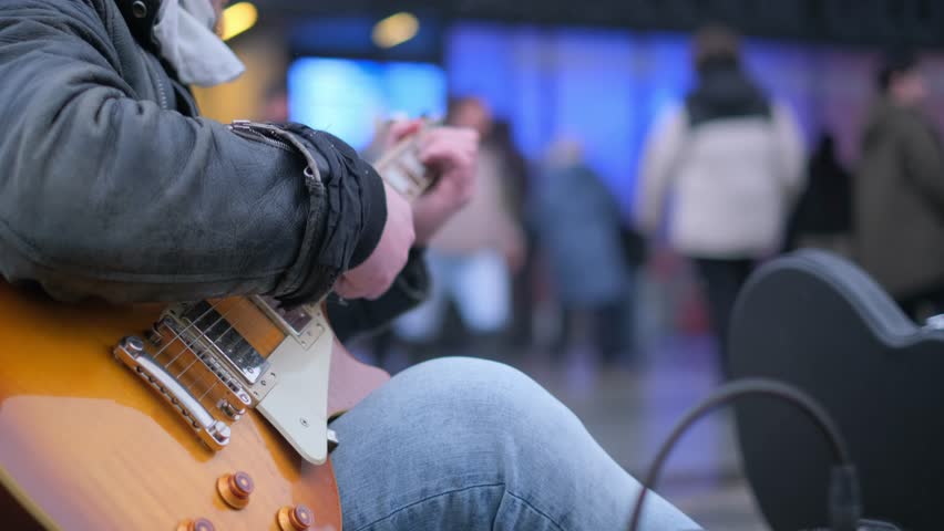 A skilled street musician plays guitar passionately in a lively urban setting, enchanting crowds