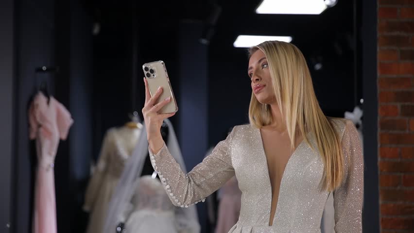 A middle-aged bride of American appearance takes a selfie in a luxurious white dress