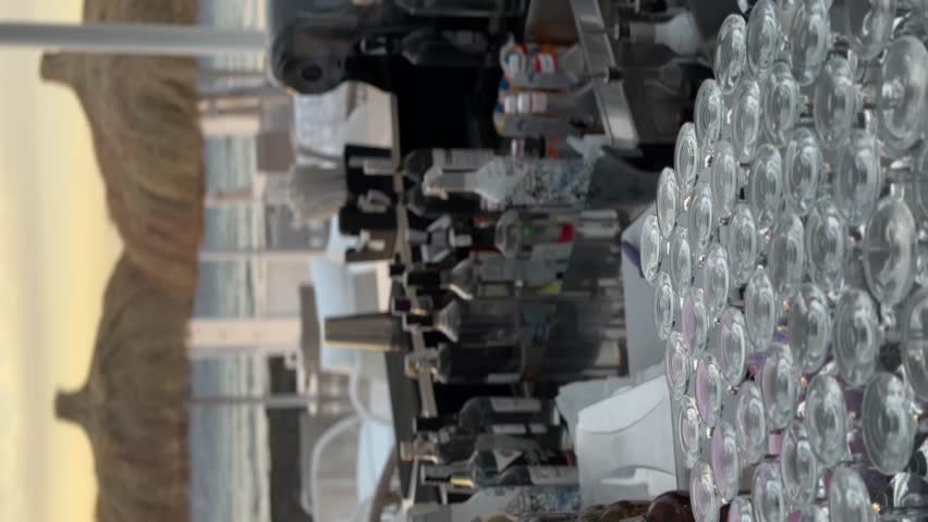 Elegant wine glasses and dining area illuminated by a golden sunset. A peaceful, serene evening view on an outdoor terrace, perfect for a relaxing drink.