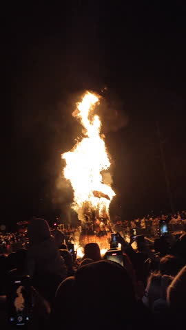 Burning of large straw effigy Winter on square on street during Maslenitsa holiday. Pagan ritual. Lots of people spectating around. Festivities festival outdoors. Vertical