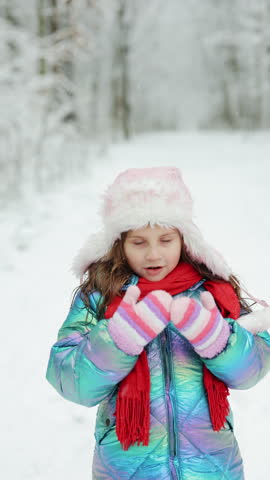 Vertical Format Video of Portrait of cute little girl in winter. Happy child in winter forest. Surprised beautiful girl who looks at the camera and smiles