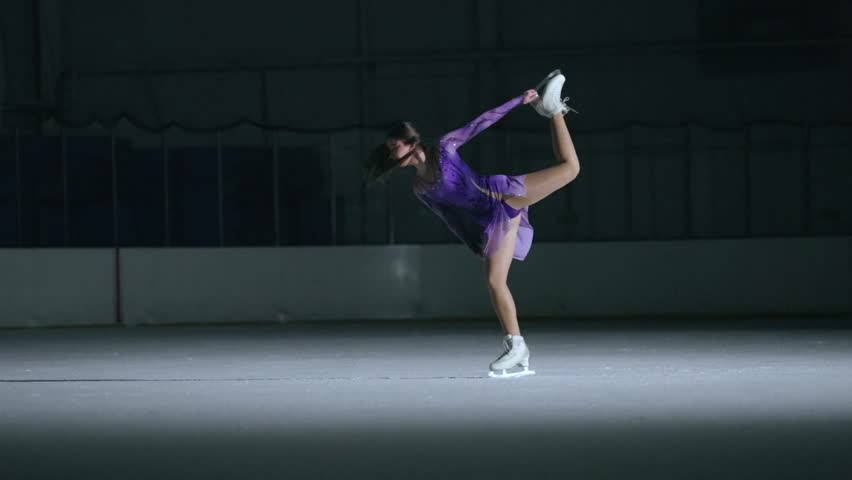 Figure skating. A figure skater girl skates alone in an ice arena at night.