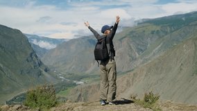 Happy woman traveler raises her arms while standing on top of a cliff admiring beautiful view of mountains. Young female hiker enjoying outdoor lifestyle in summer vacation trip. - Powered by Shutterstock - Get 15% off with code: PIKWIZARD15