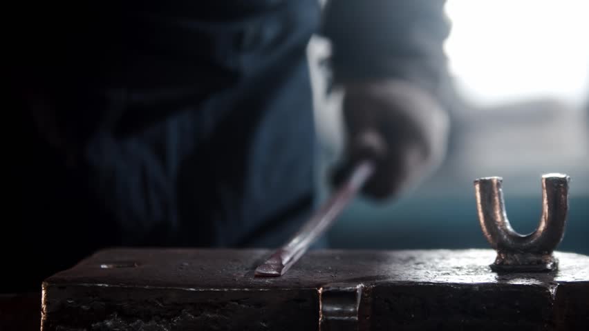 Blacksmith shaping metal on anvil with hammer