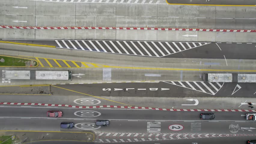 Top down view of Metropolitano buses driving in and out of a bus Plaza Flores station while cars pass by on the adjacent Luis Bedoya Reyes expressway