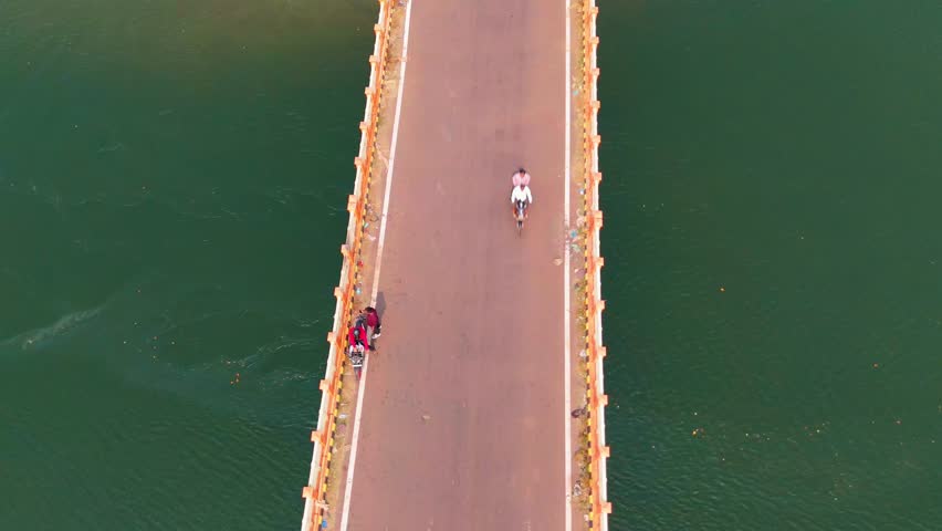Aerial View Scenic Bridge Over Water, Drone shot long viaduct run across quiet coastal stretch, Tall overpass spans sea zone, Forest surrounds both ends of concrete trail, Vehicle passes on highway