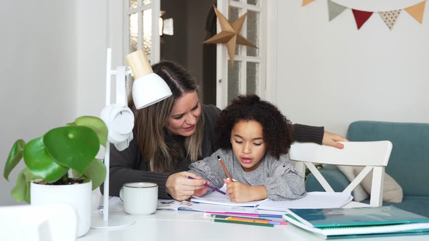 Caucasian mother and African American daughter studying at home, doing homework in cosy white room. Parent teach, child school girl learn knowledge, write exercise read book. Education for children