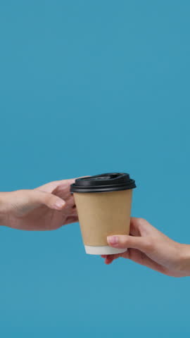 Vertical Screen : Young woman hand hold brown clear empty blank coffee paper cup for takeaway over blue background. Copy space for place a text for advertisement. Advertising area, mock up content.