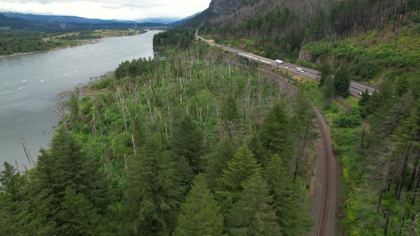 Traffic scene on river road in Oregon state during cloudy day. Beautiful nature of American during cloudy day. Aerial Tilt up wide shot.