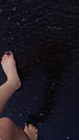 Walking Bare feet in black volcanic sand on a beach. Beaches with which are one of the attractions of the Canary Islands. Close up. Playa de la Arena, Tenerife, Spain. Slow motion