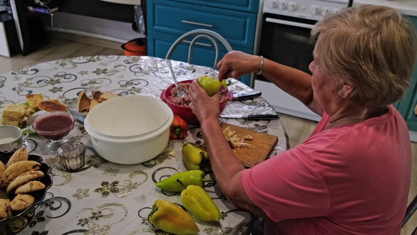 A grandmother in a pink shirt peels bell peppers while preparing a hearty homemade dish. Cooking from scratch emphasizes sustainability, mindful eating, and the joy of homemade food.