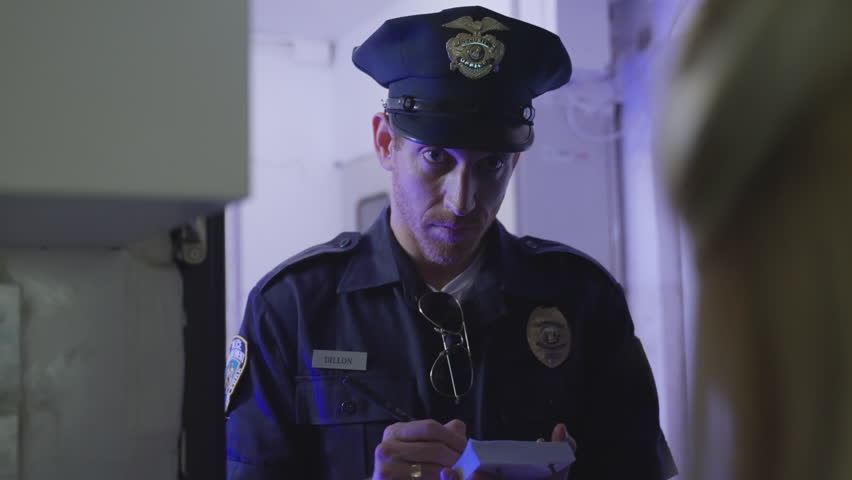Police officer at the entrance of apartment, questioning a woman while taking notes in notepad. Investigation, law enforcement, and crime-solving. Police procedures, witness statements, crime reports.