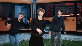 Young male dancers performing high-energy hip hop choreography near orange bus, showcasing urban street dance style with passion and coordination in outdoor evening setting - Powered by Shutterstock - Get 15% off with code: PIKWIZARD15