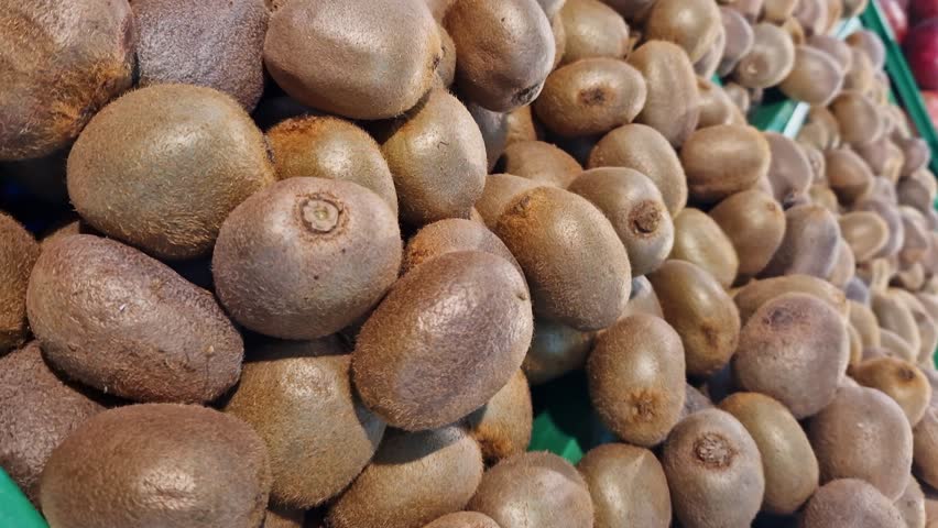 Ripe kiwis on a counter in a store or supermarket. A pile of kiwis close-up at the market. Kiwi fruits for sale