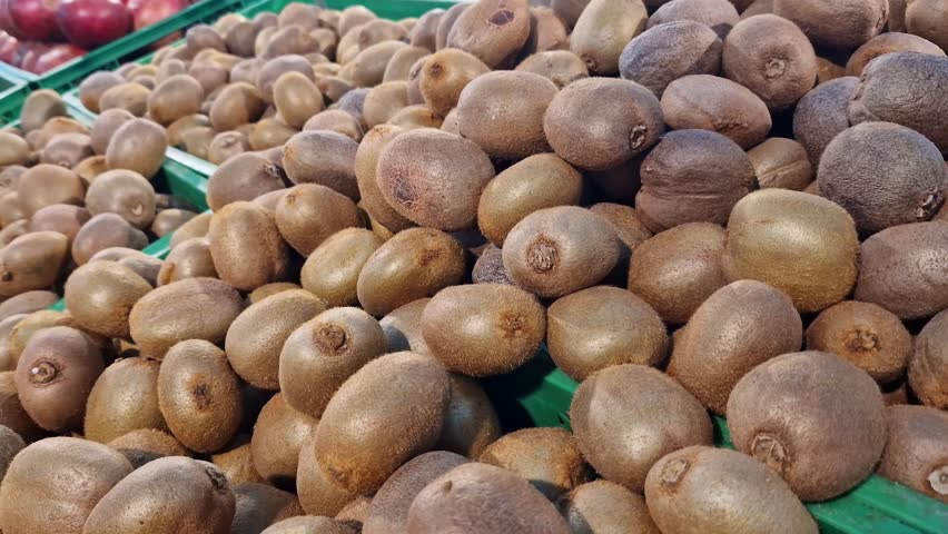 Ripe kiwis on a counter in a store or supermarket. A pile of kiwis close-up at the market. Kiwi fruits for sale