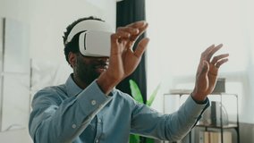 Enthusiastic African American man using VR headset and swiping image with one hand while exploring digital space. Smiling while interacting with virtual interface. Immersed in futuristic experience. - Powered by Shutterstock - Get 15% off with code: PIKWIZARD15