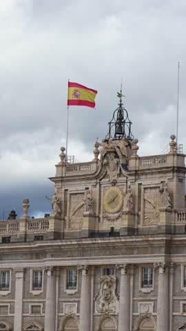 Spanish flag waving on royal palace of madrid rooftop on cloudy day. Vertical video