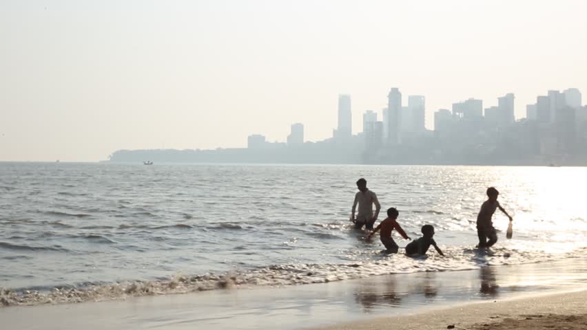 People bathing in Mumbai ocean during sunset