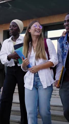 Multicultural group of students walking going out of university, leaving to go home. Front view of classmates outside of the school after class. Vertical video with copy space.