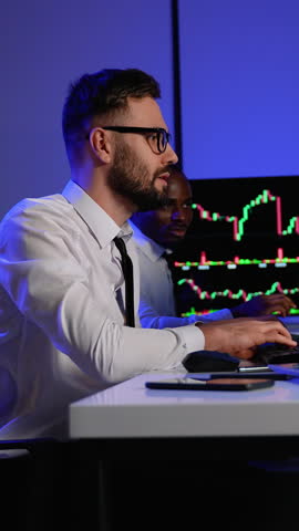 Two traders analyzing stock market data on multiple screens