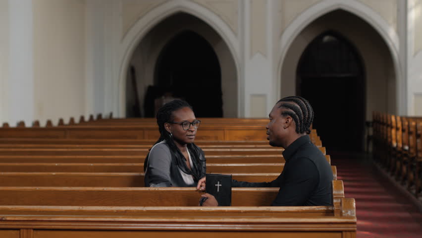 Devoted couple sharing spiritual connection while sitting closely in church pew, discussing personal faith and religious beliefs with quiet intimacy