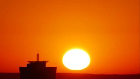 Dawn. A large solar disk rises from the horizon, hiding behind a high-rise building, against the backdrop of a clear red-orange sky. Original amazing 4k timelapse sunrise footage. - Powered by Shutterstock - Get 15% off with code: PIKWIZARD15