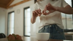 Woman carefully cracking fresh eggs into ceramic bowl, smooth slow motion movement revealing golden yolks while preparing ingredients for cooking process - Powered by Shutterstock - Get 15% off with code: PIKWIZARD15