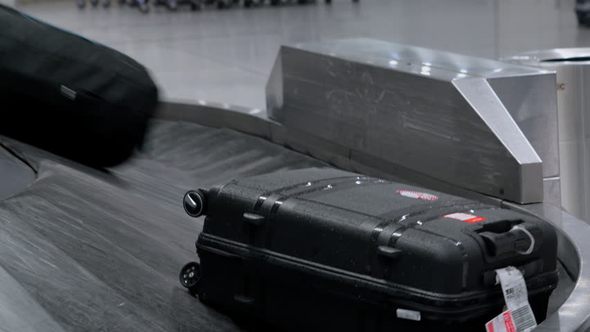 Luggage arrives at the baggage claim area in a busy airport terminal