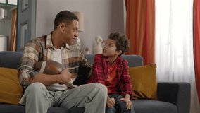 African American father cheering up upset cute teenage son with American football ball after defeat of team, expressing support and care while family spending leisure, watching sports on tv . - Powered by Shutterstock - Get 15% off with code: PIKWIZARD15