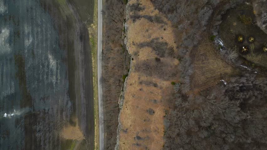 A small rural road runs along the base of a large river bluff in southern Illinois during the winter. The winter forest provides an interesting texture to the landscape.