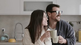 Couple wearing bathrobes enjoying morning coffee in the kitchen. 4k video - Powered by Shutterstock - Get 15% off with code: PIKWIZARD15