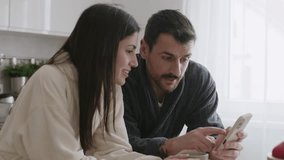 Couple using smartphone and having breakfast in the kitchen. 4k video - Powered by Shutterstock - Get 15% off with code: PIKWIZARD15