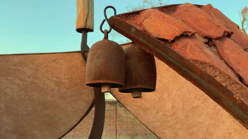 push in shot of two old rusty cattle bell hanging in the garden