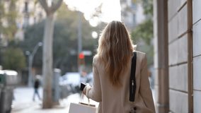 Video of happy smiling woman carrying shopping bags while walking through the city. Looking at camera - Powered by Shutterstock - Get 15% off with code: PIKWIZARD15