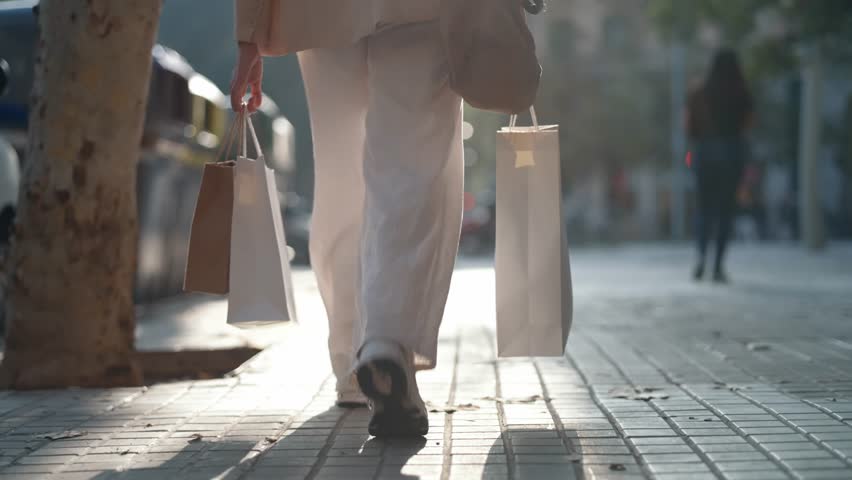Video of close up of woman carrying shopping bags walking through the city