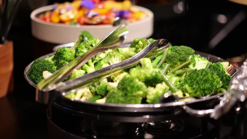 Steamed broccoli in a bowl at a buffet or catering event, fresh and ready to serve.