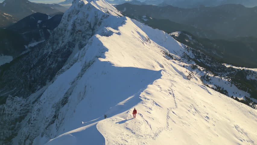 A person in red climbs a steep, snow-covered mountain slope, showcasing their determination and adventurous spirit.