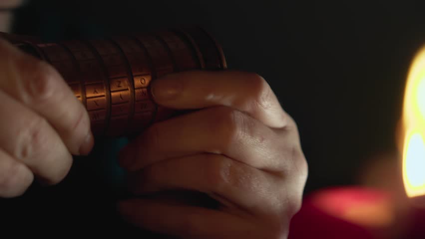 Man in Candlelit room trying to solve cryptex puzzle CLOSE-UP of hands