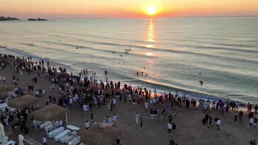 A drone footage of people gathering on the sandy shore of Constanta city at sunset, in southeastern Romania