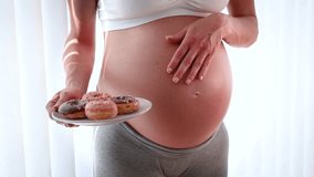 Pregnancy and unhealthy eating concept with a pregnant woman eating tasty doughnuts - Powered by Shutterstock - Get 15% off with code: PIKWIZARD15