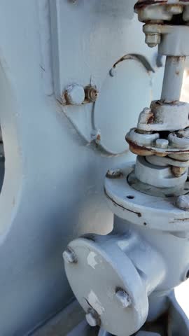 Detailed view of a vintage naval artillery mount with a metal operator seat and mechanical components, displayed on a decommissioned military ship.