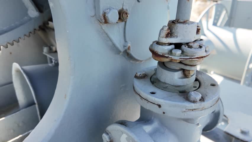 Detailed view of a vintage naval artillery mount with a metal operator seat and mechanical components, displayed on a decommissioned military ship.