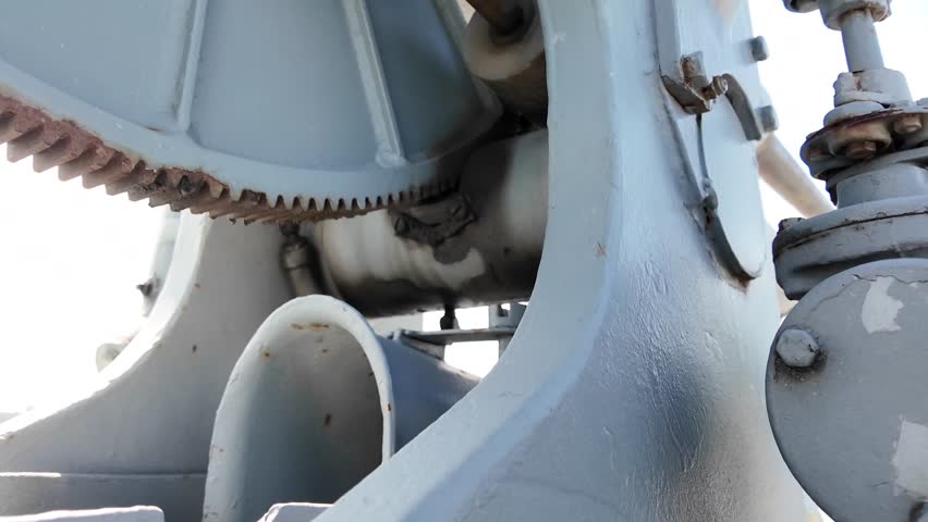 Detailed view of a vintage naval artillery mount with a metal operator seat and mechanical components, displayed on a decommissioned military ship.