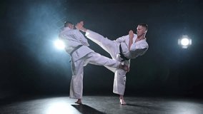 Martial arts masters on dark background. Strong man fighters in white kimono for karate martial arts fighting training in black gym. Karate fighters training punches kicks practicing fight sparring - Powered by Shutterstock - Get 15% off with code: PIKWIZARD15