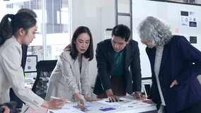 Professional Asian business team analyzing marketing performance data, collaborating over large paper charts during strategic office meeting, discussing growth strategies and innovative solutions - Powered by Shutterstock - Get 15% off with code: PIKWIZARD15