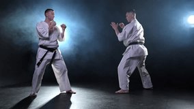 Martial arts masters on dark background. Strong man fighters in white kimono for karate martial arts fighting training in black gym. Karate fighters training punches kicks practicing fight sparring - Powered by Shutterstock - Get 15% off with code: PIKWIZARD15