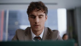 Thoughtful businessman sitting at coworking workplace with laptop computer. Pensive brunette professional thinking at table in office. Focused business man face looking documents. Serious man portrait - Powered by Shutterstock - Get 15% off with code: PIKWIZARD15