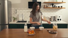 Smiling young European brunette woman pouring cereal into a bowl in the kitchen, enjoying a bright morning - Powered by Shutterstock - Get 15% off with code: PIKWIZARD15
