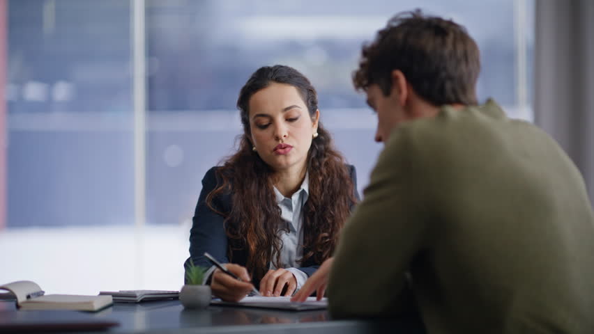 Professional consultant talking with client discussing project at panoramic cabinet office closeup. Confident woman explaining plan to man at work meeting. Two business people collaborating workplace