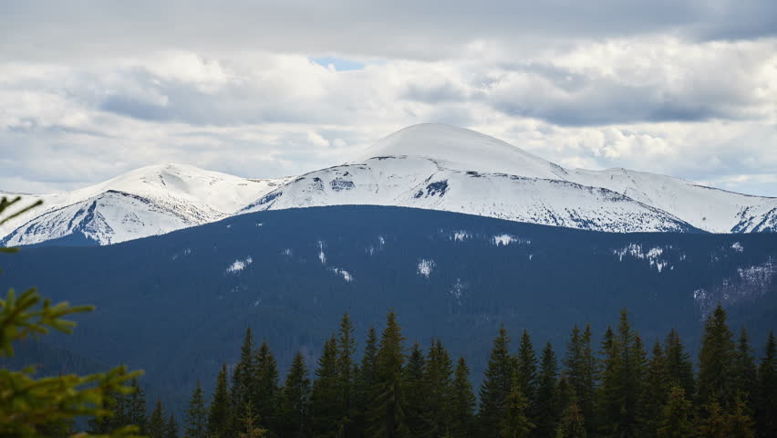 Stunning winter scene showcasing majestic, snow-covered mountain peak under cloudy sky. Mountain